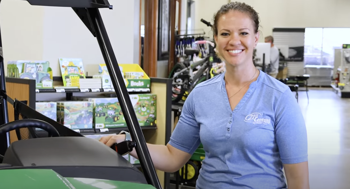 A female 21st Century Equipment employee posing next to a machine in one of our stores.